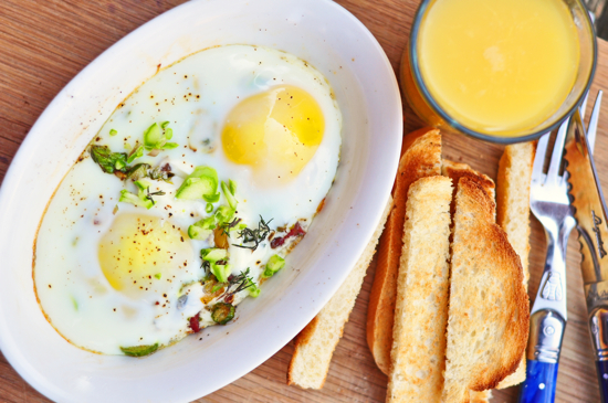 Baked eggs in a small ramekin served with orange juice and toast fingers