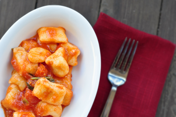 Gnocchi with simple tomato sauce in a white dish with a red napkin and a fork