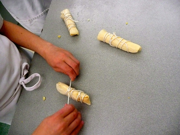 Kids rolling and tying corn husks for tamales by eatlivetravelwrite.com
