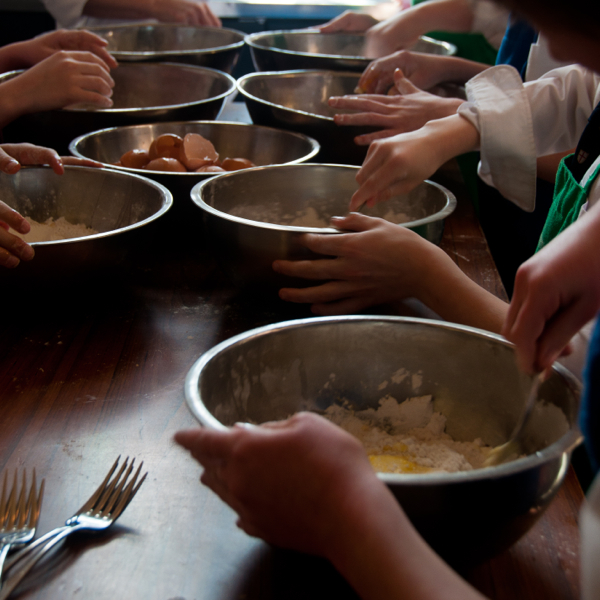 KIds mixing eggs into flour to make pasta dough on eatlivetravelwrite.com