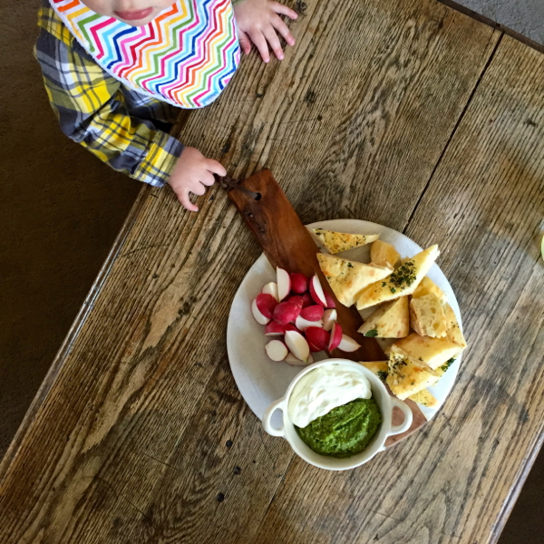 Toddler contemplating Seven Spoons blitzed ricotta with pea pesto on eatlivetravelwrite.com