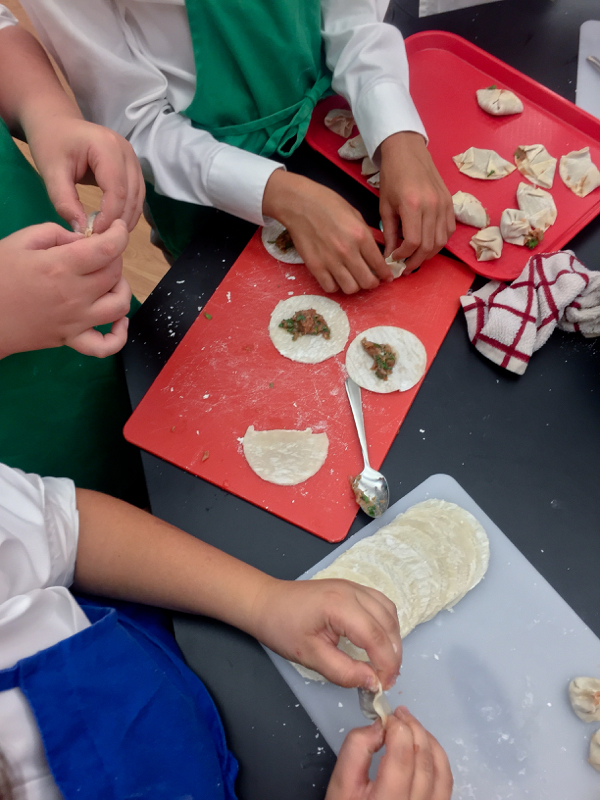 Kids busy folding dumplings on eatlivetravelwrite.com