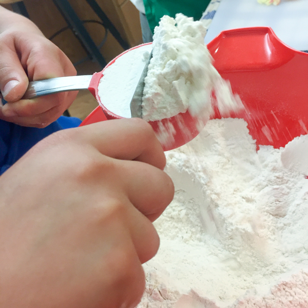 Kids scooping and sweeping flour on eatlivetravelwrite.com