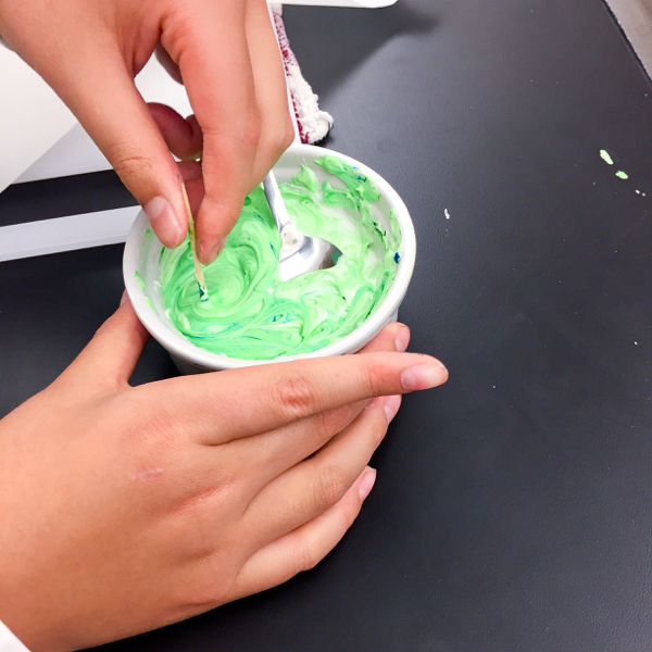 Mixing green icing for decorating cookies on eatlivetravelwrite.com