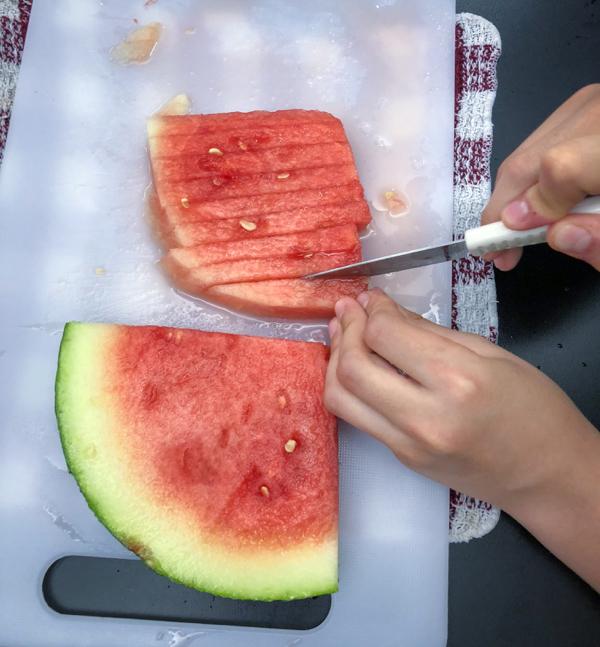 Kids slicing watermelon to make Persian watermelon salad on eatlivetravelwrite.com