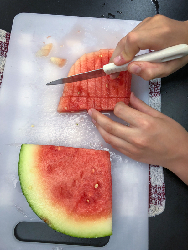 Kids cubing watermelon to make Persian watermelon salad on eatlivetravelwrite.com