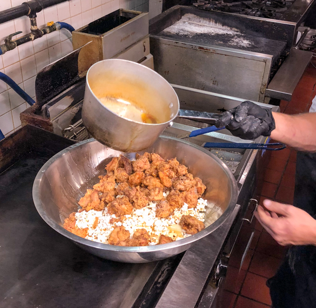 Pouring over buttery hot sauce on popcorn chicken and waffle bitsfrom Brunch Life at Lisa Marie with Matt Basile on eatlivetravelwrite.com