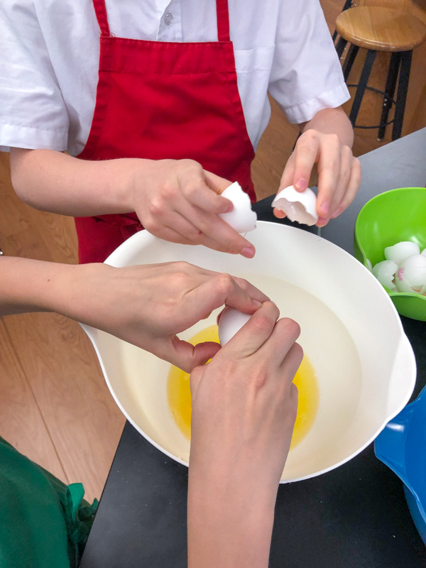 Kids cracking eggs for Bacon spinach and spaghetti frittata from Weekday Suppers by Emily Richards on eatlivetravelwrite.com