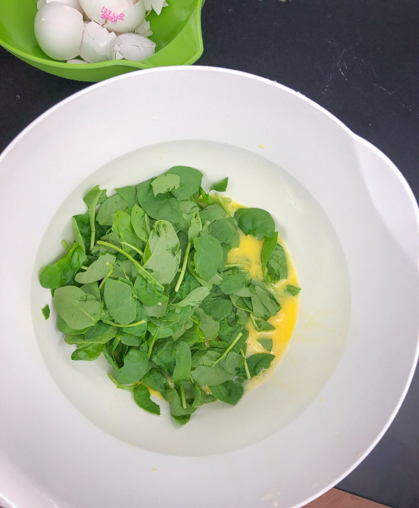Adding spinach to our mixture forBacon spinach and spaghetti frittata from Weekday Suppers by Emily Richards on eatlivetravelwrite.com