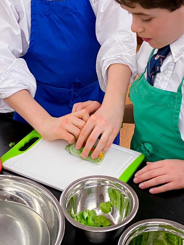 Kids teaching others how to make to make fresh rolls with mango with Vanessa Yeung on eatlivetravelwrite.com