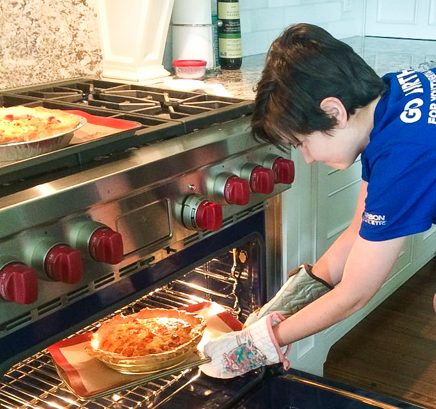 Kids putting a tomato quiche in the oven