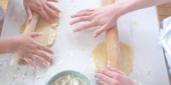 Kids rolling pastry dough on a marble surface