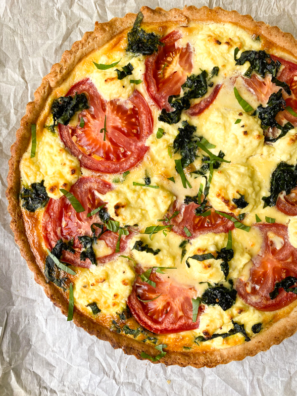 Dorie Greenspan's Tomato Tart with Mustard and Ricotta on a baking tray lined with parchment paper.