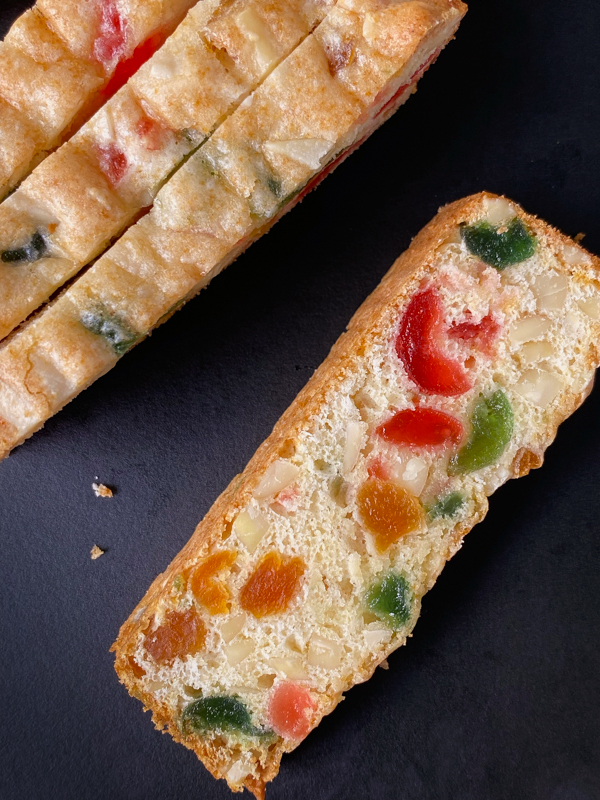 A slice of almond and fruit bread on a black tray.