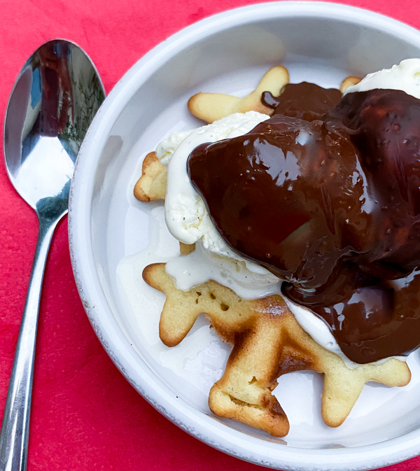 Mini waffles topped with ice cream and melted chocolate.