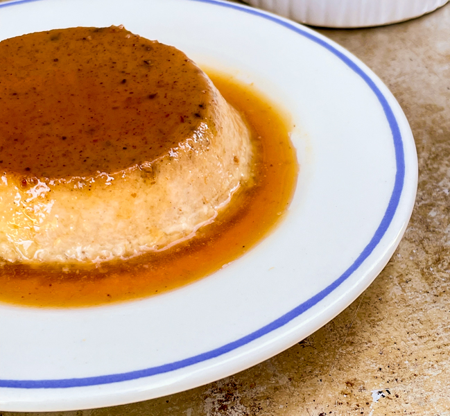 Pumpkin Crème Caramel on a plate surrounded with caramel sauce.