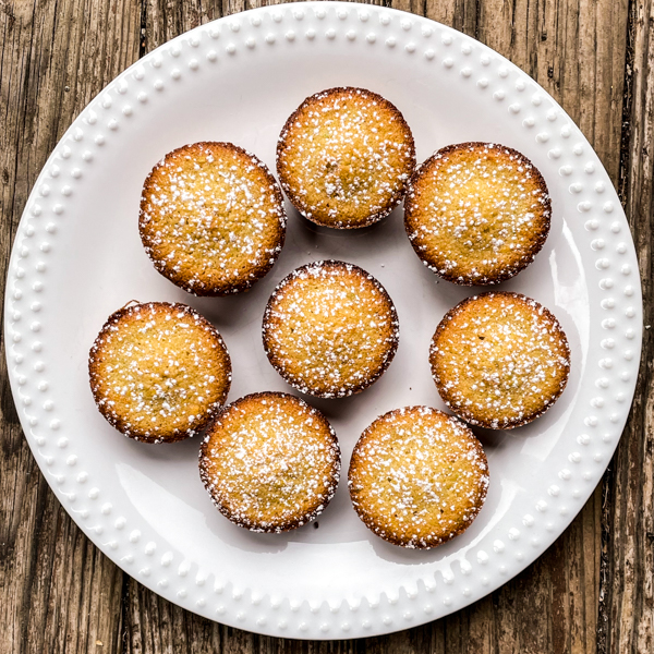 Citrus financiers on a white plate on a wooden table.