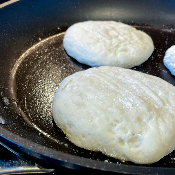 English muffins cooking in a skillet.