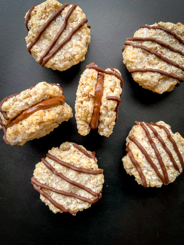 Chocolate hazelnut sandwich cookies on a black serving tray.