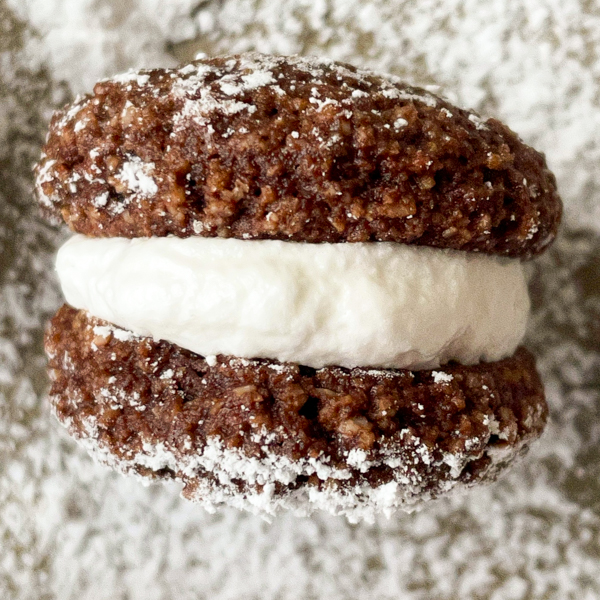 Chocolate cookie with marshmallow filling on a baking dray sprinkled with icing sugar.