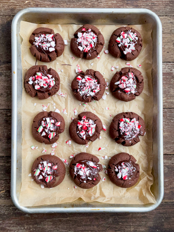 A tray of chocolate mint thumbprint cookies topped with candy canes.