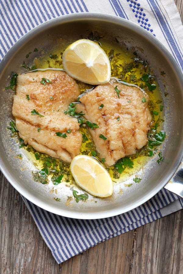 Fish in buttery lemon sauce in a small skillet.