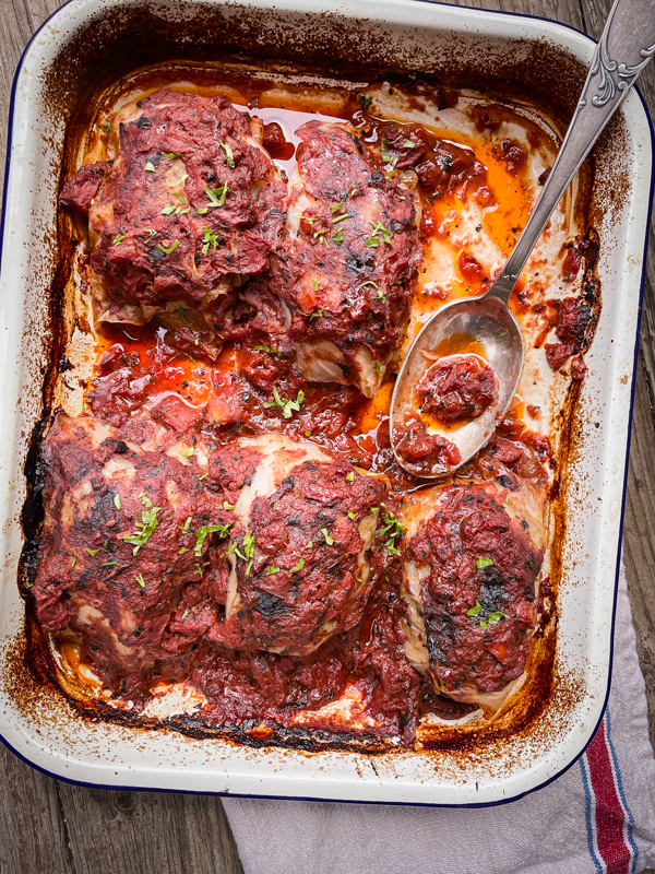 Stuffed Cabbage from Everyday Dorie in a baking dish with a spoon of the sauce.