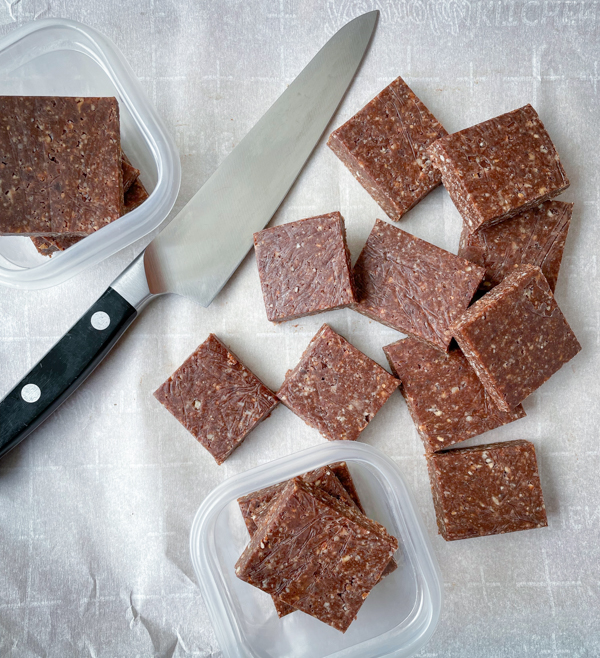 No-bake chocolate hazelnut energy squares on a baking tray lined with parchment with a knife.
