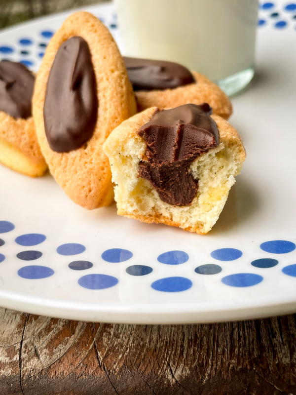 Close up of Chocolate Barquette cookies on a plate with a glass of milk.