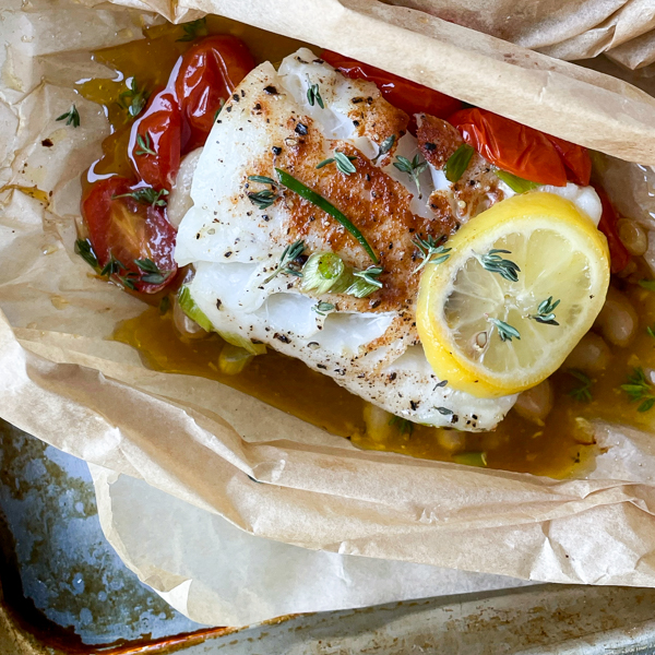 Cod baked in parchment paper with lemon and tomatoes.