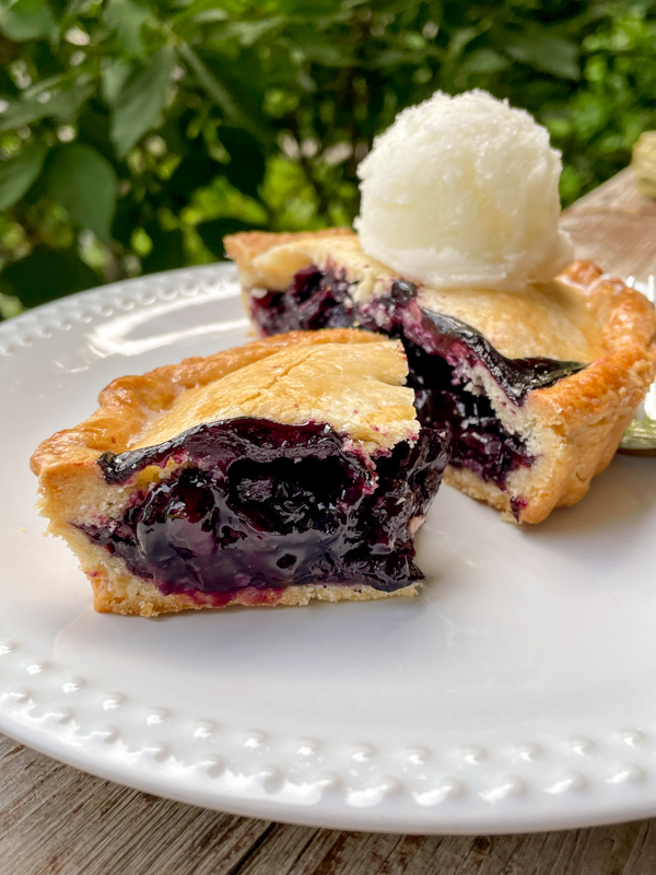 A slice of Dorie Greenspan's mini Blueberry Cherry Pie topped with ice cream.