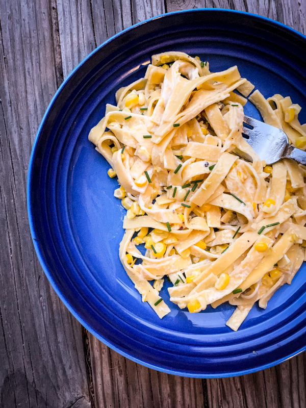 A blue plate with a serve of Butter-Poached Corn with Egg Noodles.