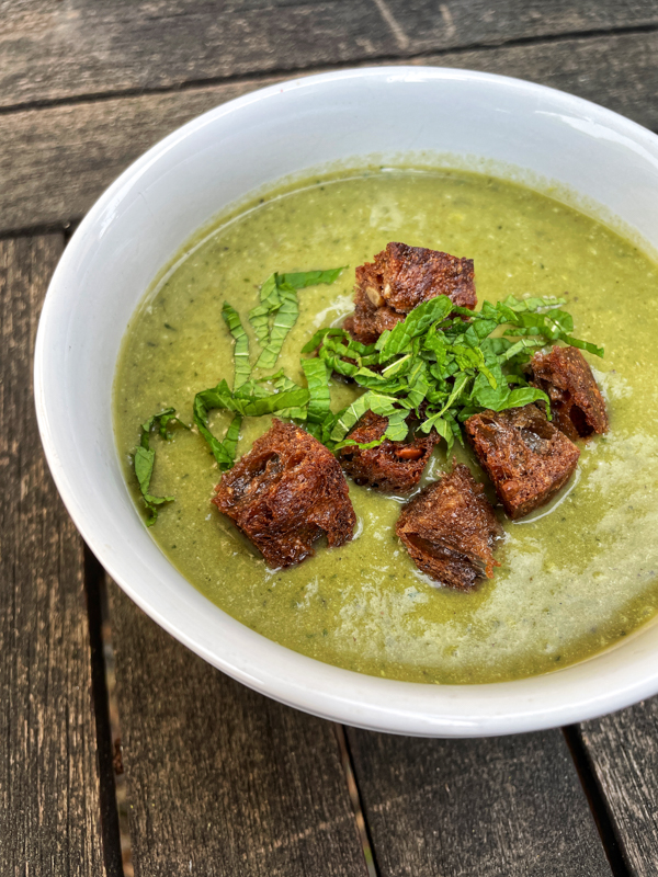 Dorie Greenspan's lettuce soup in a white bowl topped with rye croutons and thinly chopped mint.