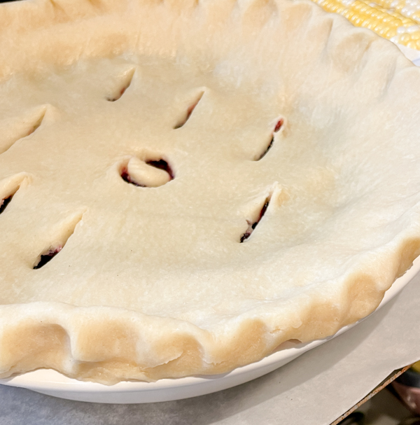 Berry pie about to be baked on a tray lined with parchment paper.