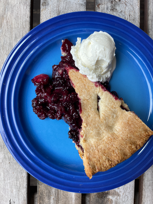 Dorie Greenspan's Mixed Berry Pie from Everyday Dorie on a blue plate with a scoop of vanilla ice cream.