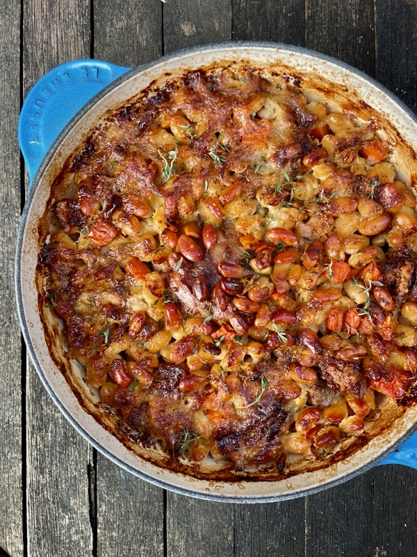 Sylvie Bigar's Gateway Cassoulet from her book Cassoulet Confessions in a blue Le Creuset Dutch Oven on a wooden surface.