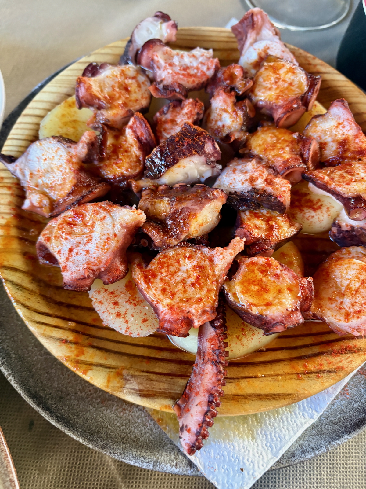 Sliced grilled octopus tentacles sprinkled with paprika on a wooden plate