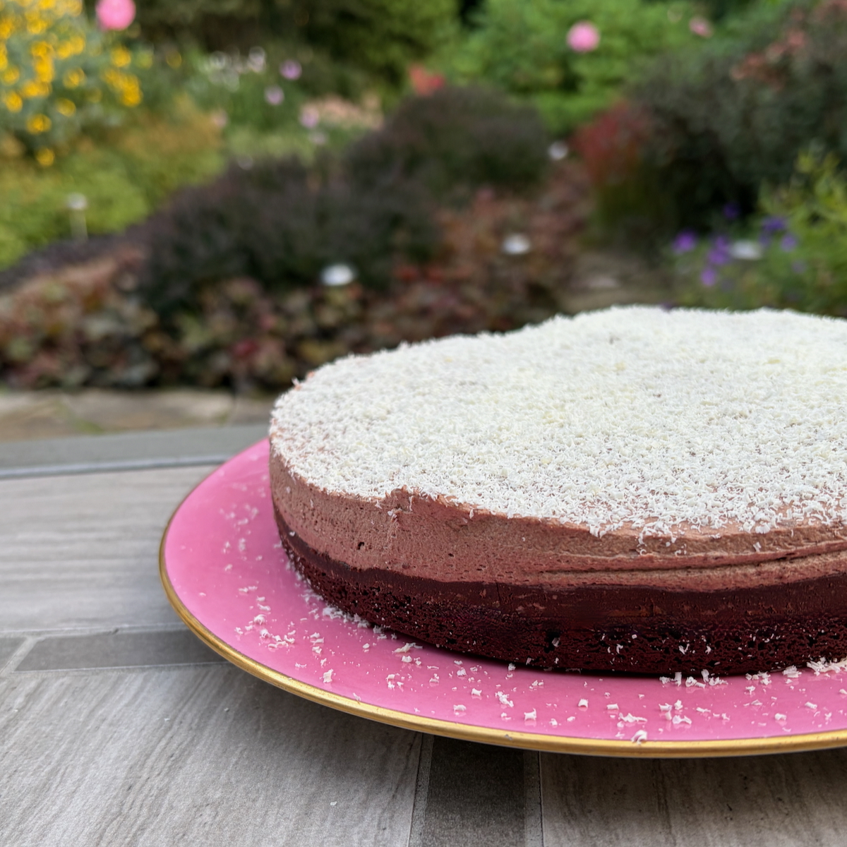 Dorie Greenspan's Lisbon Cake on a pink plate with a garden in the background.